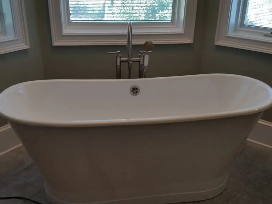 Freestanding white soaking tub beside windows